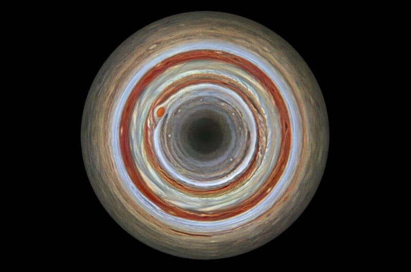 A top-down view of Jupiter’s atmosphere, centered on the north pole, showing concentric, colorful bands of clouds and storms, including the prominent reddish-brown Great Red Spot, against a black background.