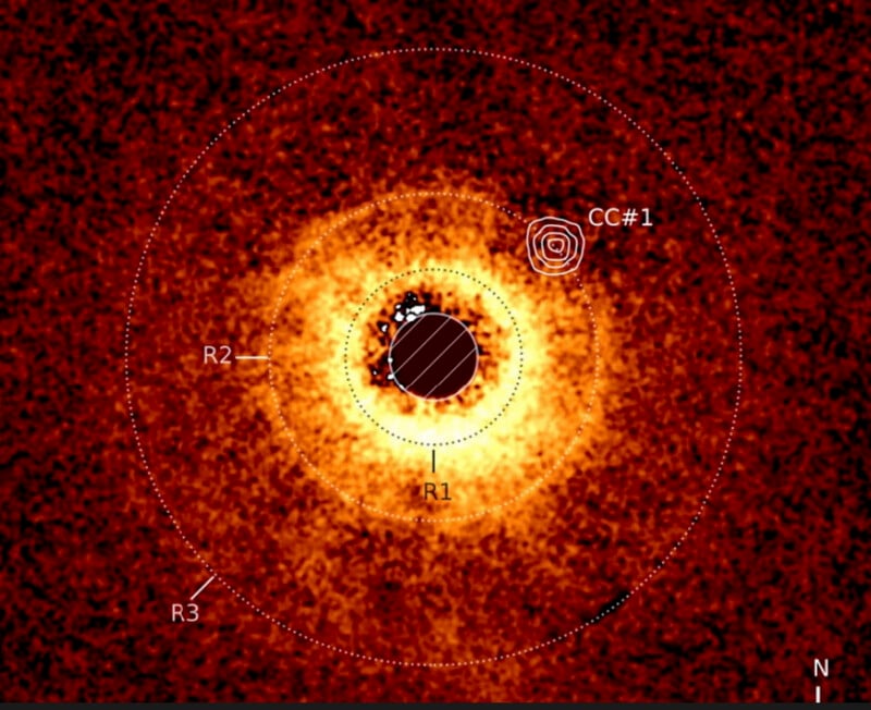 A false-color astronomical image shows a bright circular disk with concentric rings labeled R1, R2, and R3, and a marked object labeled CC#1; dotted circles and a north arrow are also visible.