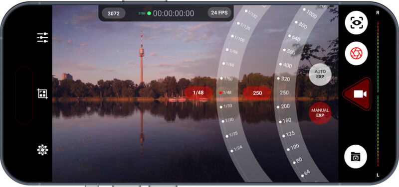 A smartphone screen displays a camera app interface with manual exposure settings over a scenic lakeside view, featuring a tall tower, trees, and reflections on calm water at sunset.