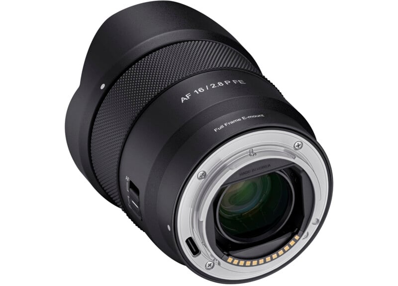 A close-up photo of a camera lens showing the metal lens mount, glass elements, and electronic contacts. The text “AF 16/2.8 FE” and “Full Frame E-mount” is visible on the lens barrel.