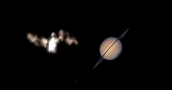 A blurry, bright object resembling the Bat-Signal appears on the left, while the planet Saturn with visible rings is clearly seen on the right, both set against a black background.