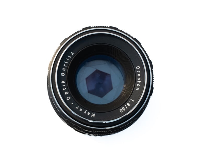 A close-up, top-down view of a vintage Meyer-Optik Görlitz Oreston 1.8/50 camera lens against a white background.