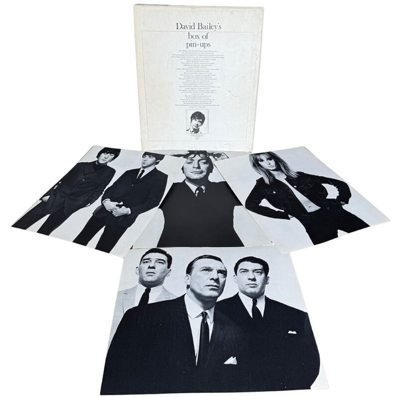 A white box with "David Bailey's box of pin-ups" on the cover stands behind three black-and-white portrait prints of famous 1960s figures arranged in front of it.