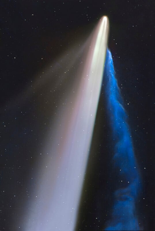 A bright comet streaks through space, displaying a wide white dust tail and a narrow blue ion tail against a dark, star-filled background.