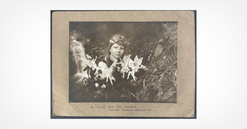 A vintage black-and-white photo of a girl outdoors with paper cutout fairies placed in front of her, blending into the natural background. The caption reads, "A Slide and the Fairies.