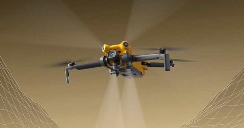 A yellow quadcopter drone with a mounted camera is flying forward against a brown background, with faint digital grid lines representing terrain or mapping data underneath its wings.