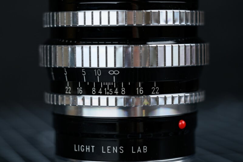 Close-up of a camera lens focusing ring showing distance and aperture markings, with the brand 