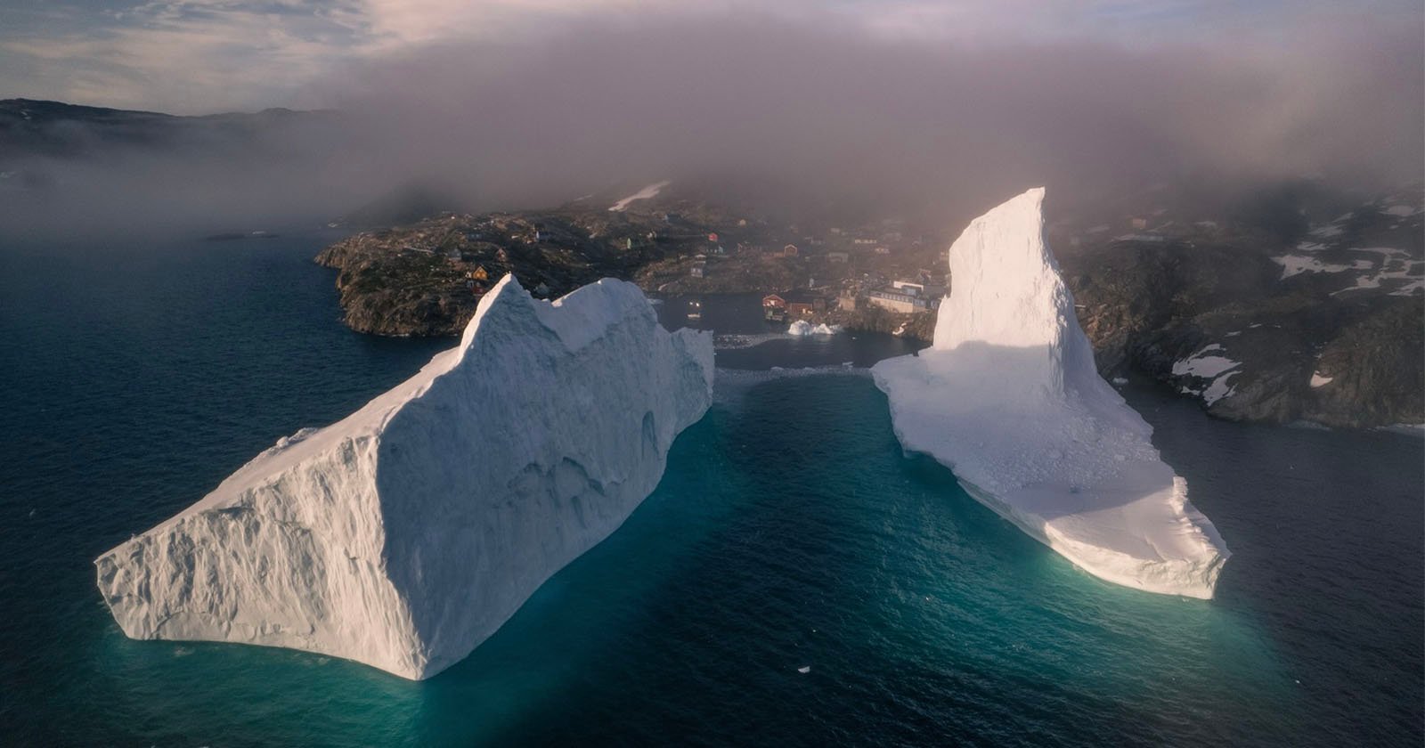 Surreal Photos of Gigantic Icebergs Looming Over a Tiny Village