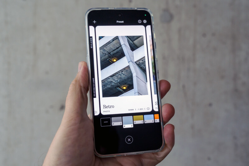 A hand holds a smartphone displaying a photo editing app with an architectural photo on screen. Various filter options, including one named "Retro," are visible at the bottom of the app.