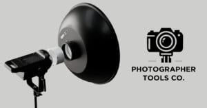 A black studio light with a reflector dish is positioned on the left. On the right, there is a camera logo and the text "Photographer Tools Co." on a light gray background.