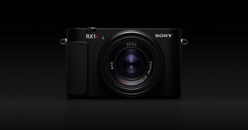 A black Sony RX1R II digital camera with a prominent Zeiss lens, shown from the front against a solid black background.