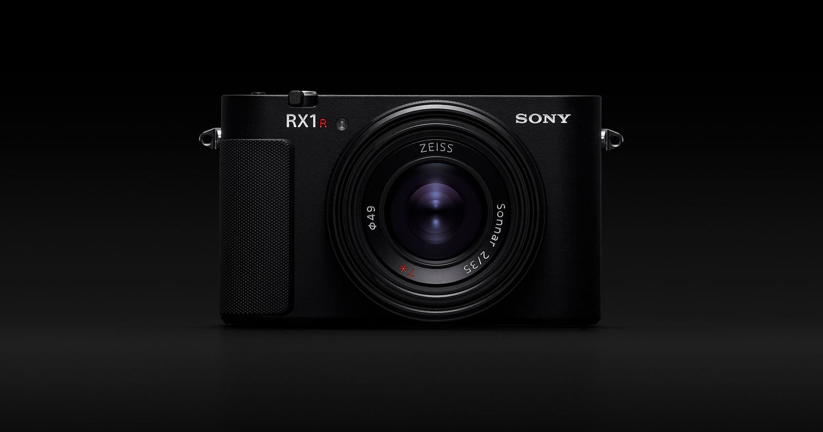 A black Sony RX1R II digital camera with a prominent Zeiss lens, shown from the front against a solid black background.