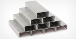 A stack of metal staples arranged in a pyramid shape on a white background.