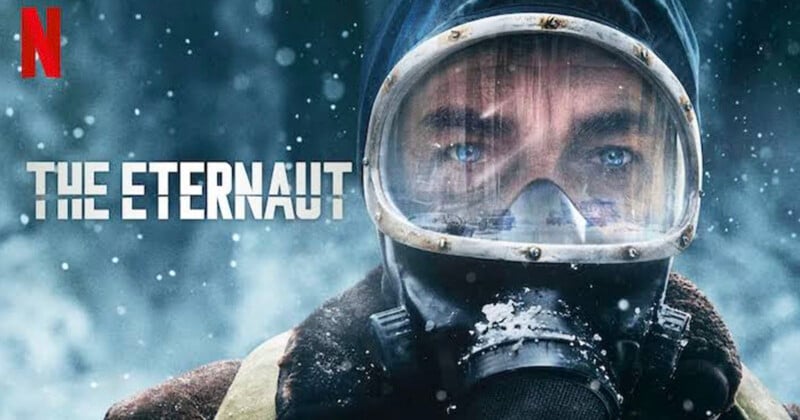 Close-up of a person wearing a gas mask and hooded coat with snow falling, against a snowy background. Text reads "The Eternaut" with the Netflix logo in the top left corner.