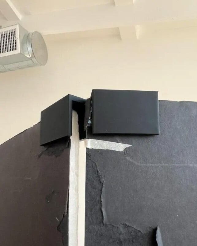 A poorly aligned door frame with black panels, revealing a noticeable gap and uneven edges at the top where the two sides meet. The construction appears unfinished or misaligned.