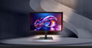 A computer monitor displaying a vibrant, abstract infinity symbol stands on a modern circular platform, with a curved concrete staircase and walls in the background.