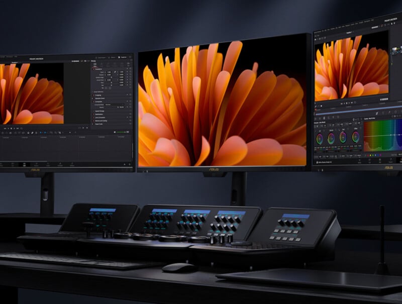 A modern video editing workstation with three monitors displaying vibrant orange flower petals and editing software, along with an advanced control panel and keyboard on a dark desk.