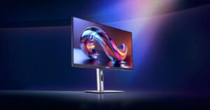 A sleek ASUS computer monitor sits on a modern stand, displaying a colorful abstract swirl on its screen against a dark, softly glowing background.