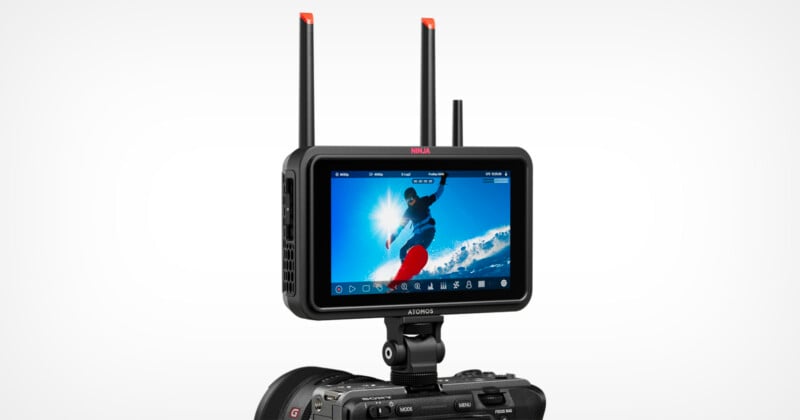 A digital camera with a mounted Atomos Ninja video monitor displaying a snowboarder mid-air against a bright blue sky, with two antennas extending from the monitor for wireless connectivity.