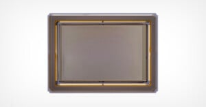 Close-up view of a rectangular camera sensor with a metallic frame and gold wiring visible along the edges, set against a plain white background.