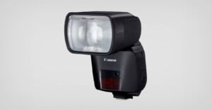 A Canon external camera flash unit with a rectangular flash head and a black body, shown against a plain light grey background.