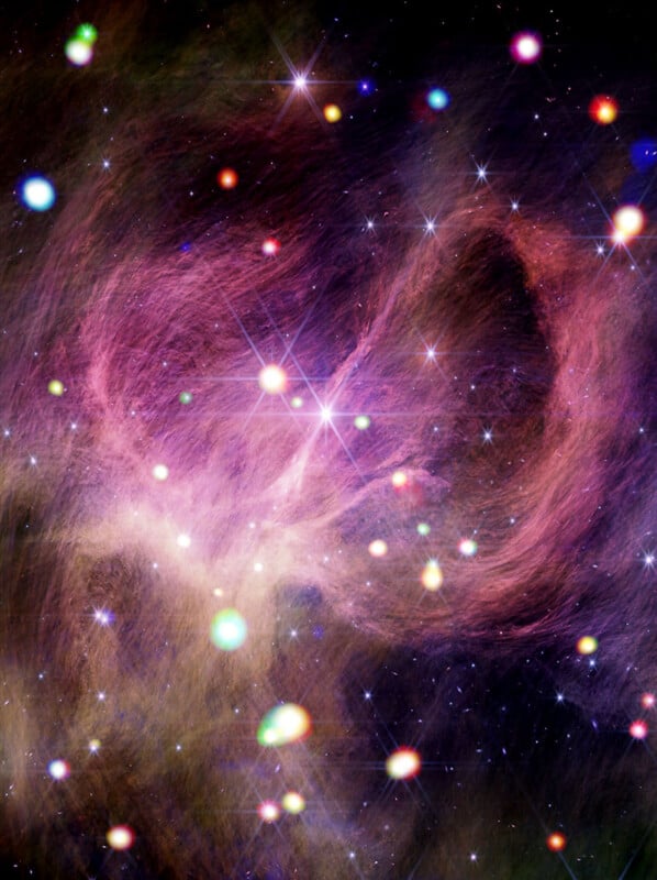 A colorful cosmic scene featuring a nebula with swirling pink and purple gas clouds and bright, glowing stars scattered across a dark space background.