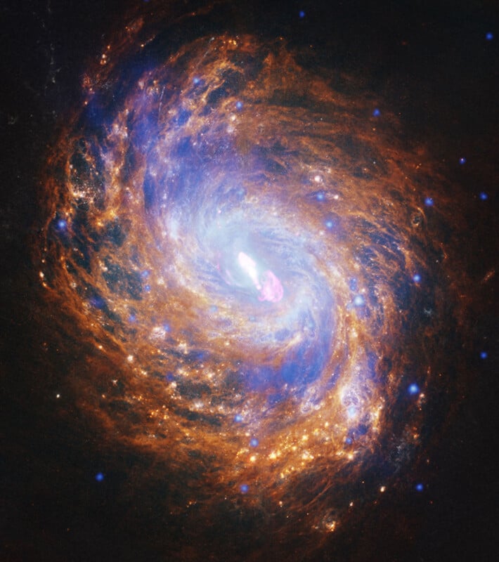 A swirling galaxy with bright stars and glowing clouds of blue, orange, and yellow gas, centered around a bright white core, set against the darkness of space.