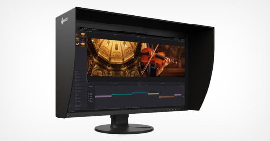 A computer monitor with a hood displays video editing software, showing footage of a violinist and ornate golden architecture on the screen. The background is plain white.