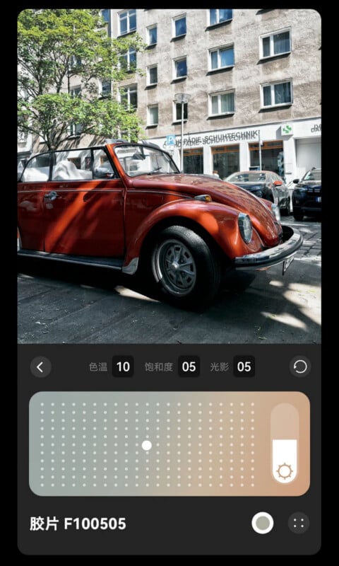 A red vintage Volkswagen Beetle is parked on a sunny street lined with apartment buildings. The lower part of the image shows a photo editing app interface with color, saturation, and lighting adjustment sliders.