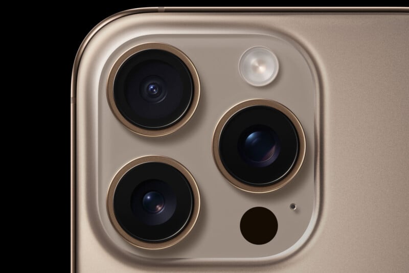 Close-up of the top corner of a gold smartphone showing three camera lenses, a flash, and a small sensor on the back.