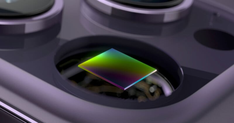 A close-up of a smartphone camera module showing a colorful, reflective sensor beneath the camera lens. The surface of the sensor displays a gradient of green, blue, and purple hues.