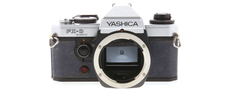 A vintage Yashica FX-D Quartz 35mm film camera without a lens, showing the lens mount and viewfinder on the front against a white background.
