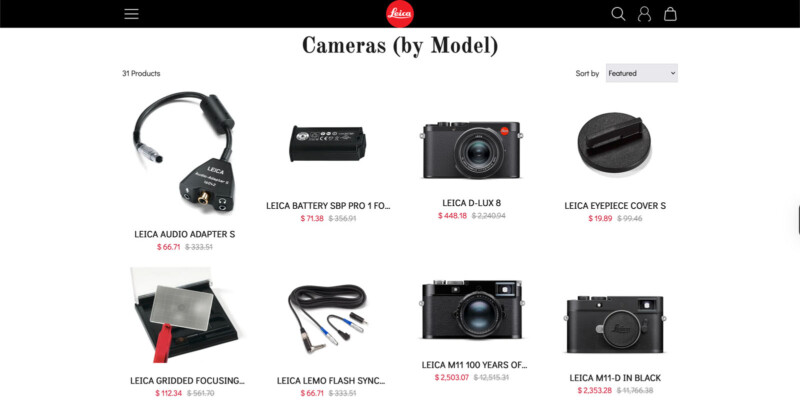 Screenshot of an online store page displaying various Leica camera models and accessories with product images, names, prices, and discounts arranged in a grid layout under the heading "Cameras (by Model).
