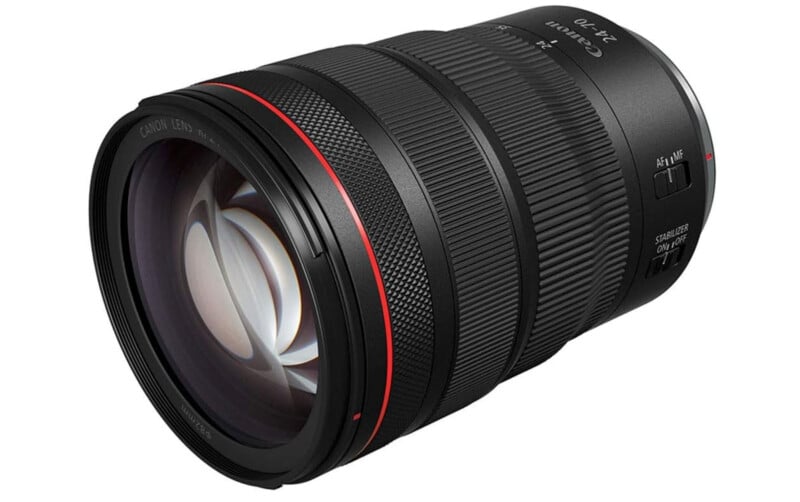 A close-up view of a Canon RF 24-70mm zoom camera lens, showing detailed focus and zoom rings, control switches, and a prominent red ring near the front element.