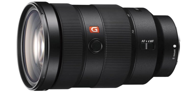 A black Sony G Master camera lens with zoom and focus rings, a focus mode switch, and an E-mount label, viewed from a slight angle showing the front glass element and side controls.