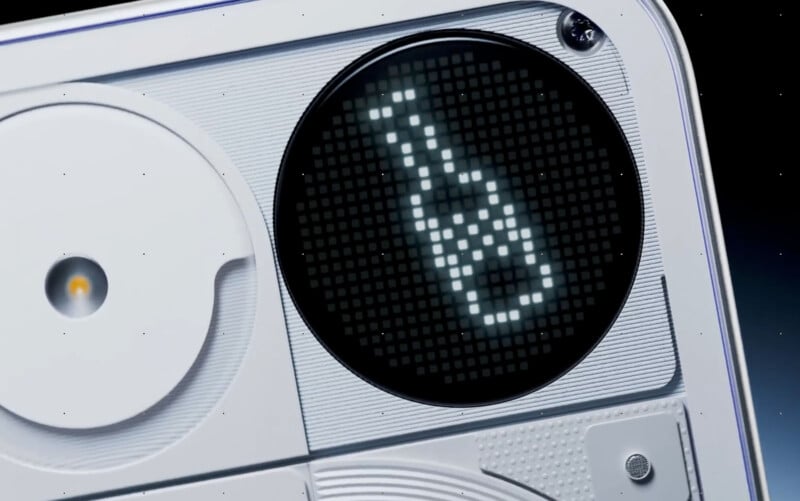 A close-up of an electronic device with a circular digital display showing a pixelated bottle icon on a black background. The device has a white, modern design with textured and smooth surfaces.