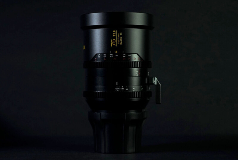 A black camera lens with yellow and white markings is positioned upright against a dark background, with measurement numbers and focus settings visible on the side.