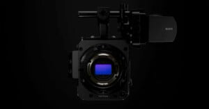 A Sony digital cinema camera body is shown head-on against a black background, highlighting its large full-frame sensor and lens mount with various controls visible.