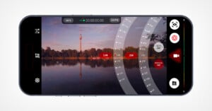 A smartphone screen displays a camera app interface showing a lake and a distant tower at sunset, with manual exposure and focus settings visible on the right side of the screen.