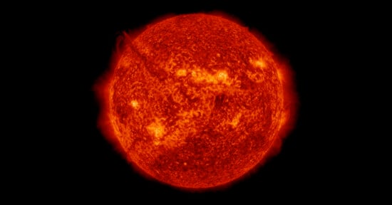 A bright, detailed image of the Sun shows its fiery, orange-red surface with visible flares, prominences, and textured patterns against a black background.