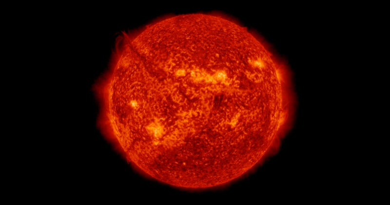A bright, detailed image of the Sun shows its fiery, orange-red surface with visible flares, prominences, and textured patterns against a black background.