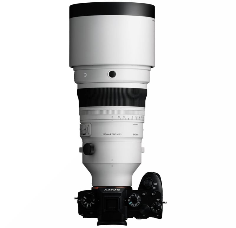 A large white telephoto camera lens attached to a black Sony digital camera body, viewed from above on a white background.