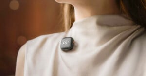 A person wearing a light-colored shirt has a small, square-shaped DJI microphone clipped near their collarbone.