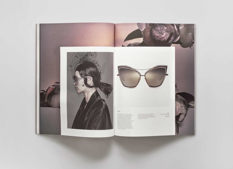 An open magazine shows a black-and-white portrait of a woman in sunglasses and a netted veil on the left page, and a large photo of stylish, cat-eye sunglasses on the right page, with flower images in the background.