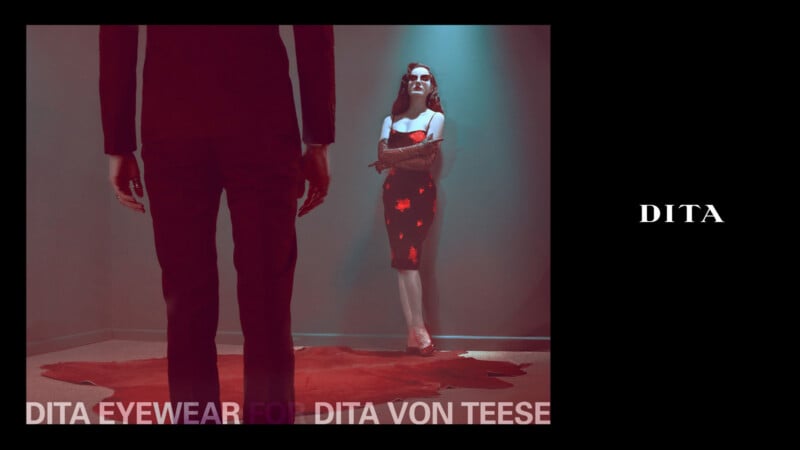 A woman in a red dress and sunglasses stands confidently on a red rug, arms crossed, while a person in a dark suit faces her. Text reads "DITA EYEWEAR FOR DITA VON TEESE" and "DITA" on a black background.