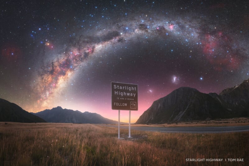 A road sign labeled "Starlight Highway" stands beside an empty road at dusk, with mountains in the background and a vivid arch of the Milky Way galaxy glowing brightly in the night sky above.