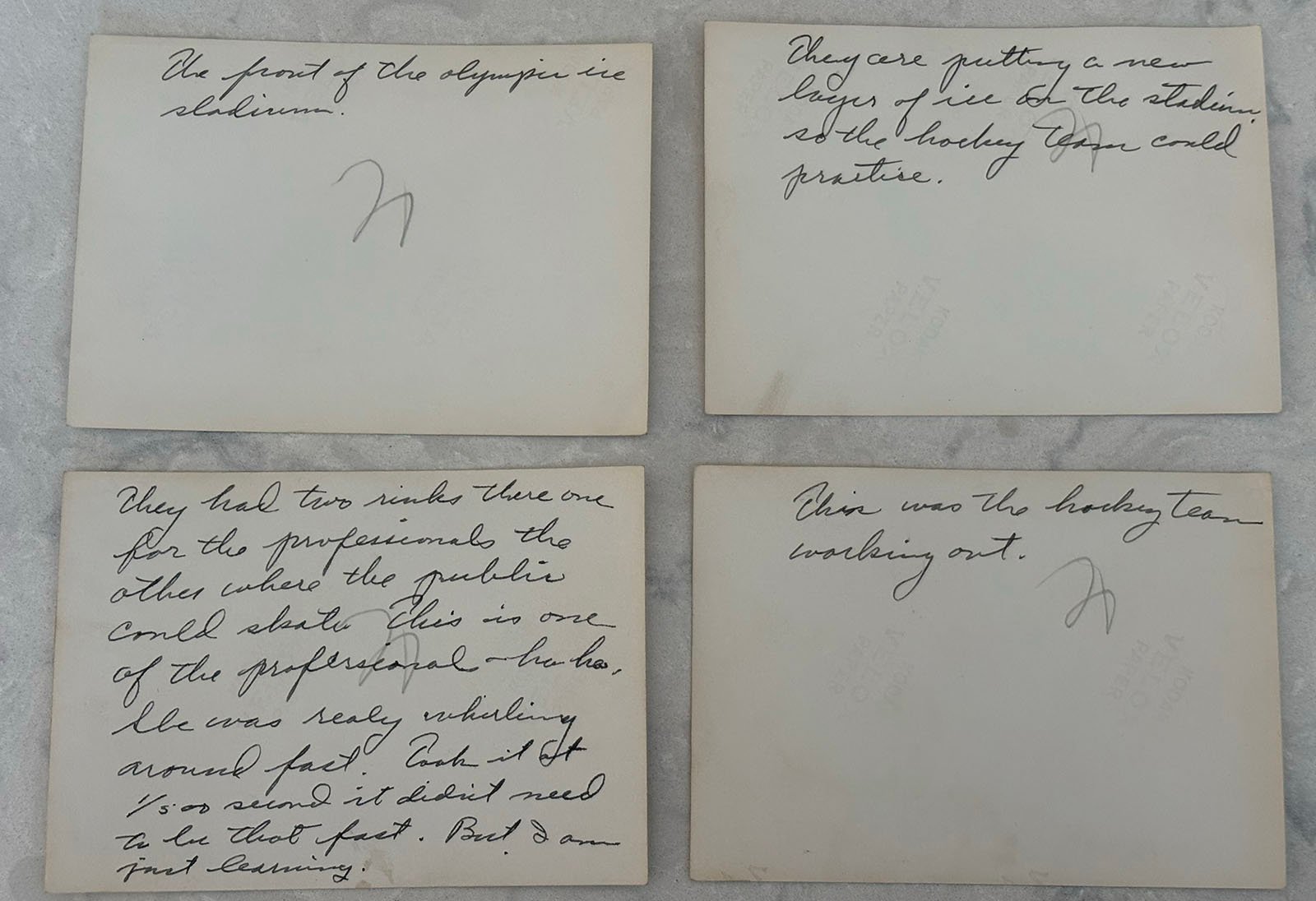 Four vintage cards with handwritten cursive notes referencing an Olympic ice stadium, a hockey team, and distinctions between professional and public use; cards are placed on a light-colored surface.