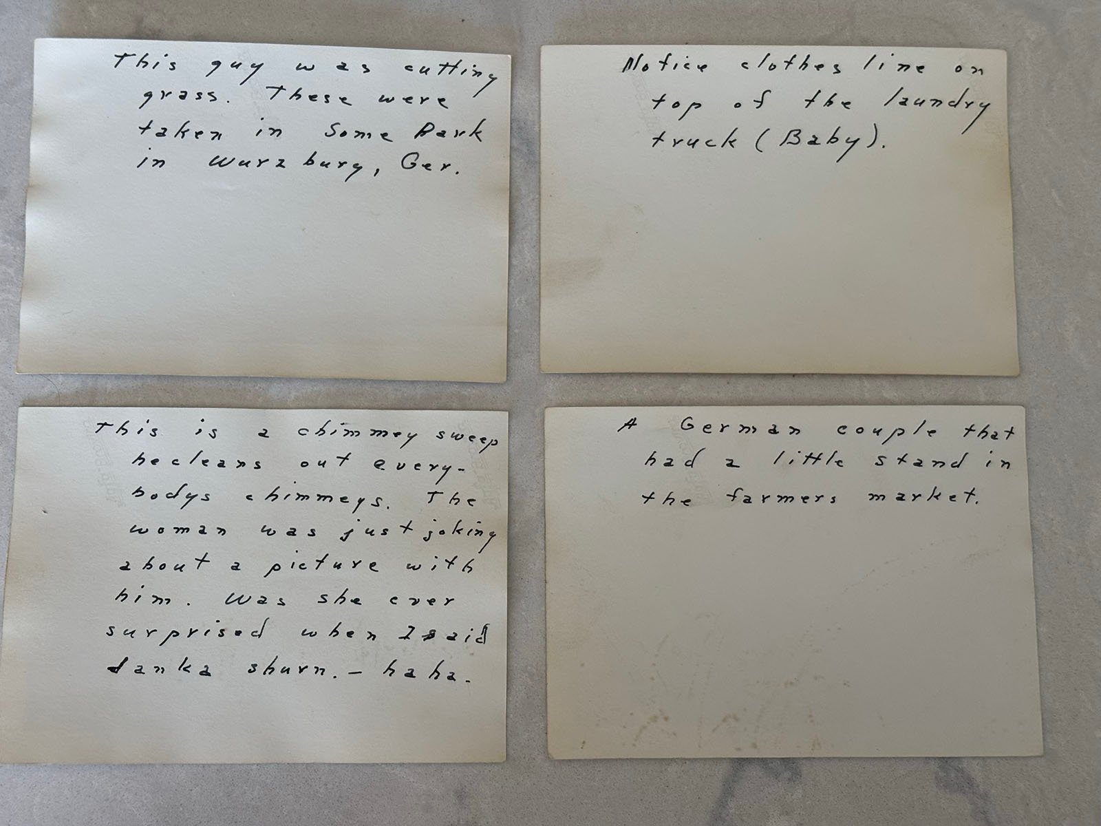 Four handwritten notes on paper. The notes describe different scenes, including a man cutting grass, a laundry truck, chimneys in a city, and a German couple at a farmers market.