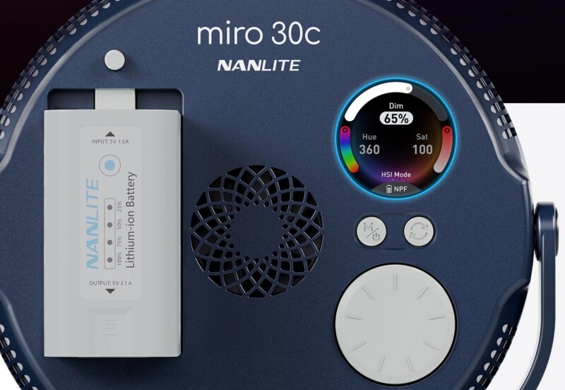 Close-up of a Nanlite Miro 30c device showing its battery, circular air vent, and a digital display with settings for hue, saturation, intensity, and battery percentage (65%).