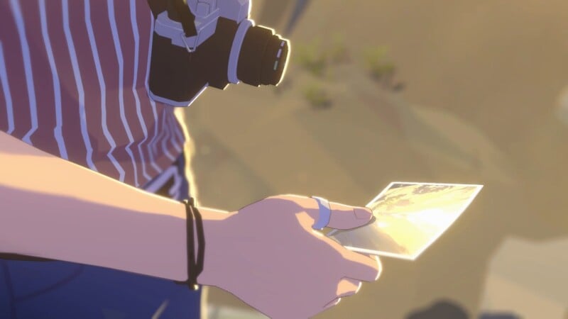 A person wearing a striped shirt and camera around their neck holds a photograph in their hand, standing outdoors in soft, golden sunlight.